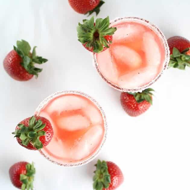 Overhead Two margarita glasses with salted rims and strawberries 