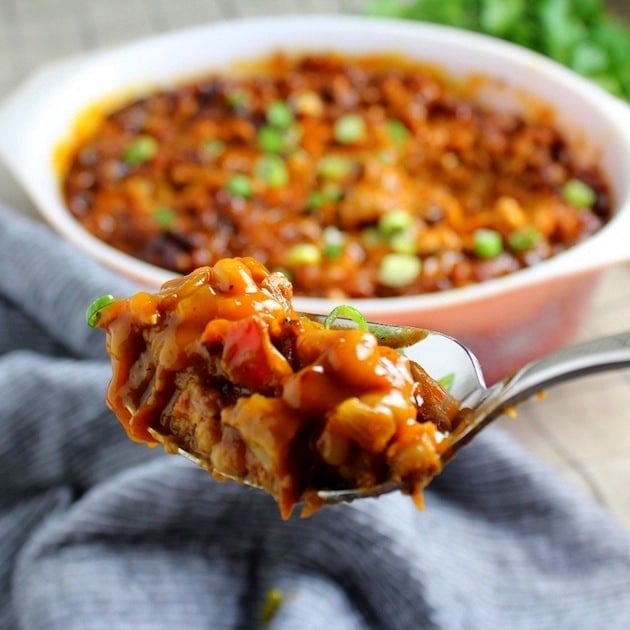Spoonful of BBQ Baked Beans with serving dish in the background