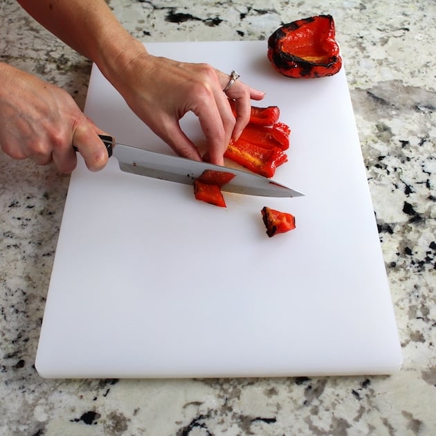 Chopping grilled red pepper on cutting board