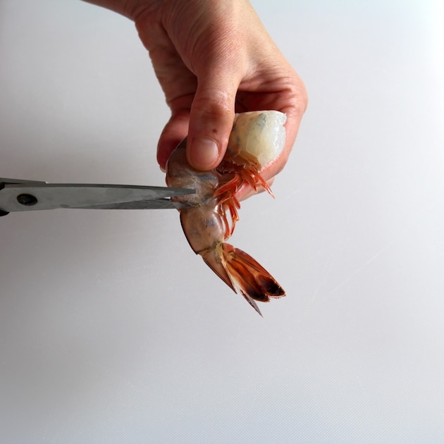 Using kitchen shears to remove shell from shrimp