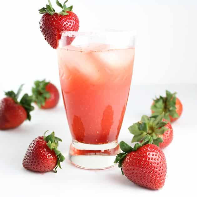 Red drink in glass with salted rim and fresh strawberries