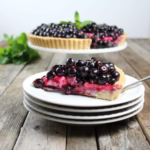 Slice of Blueberry tart on stack of serving plates