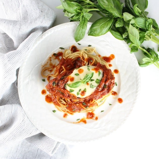 Chicken Breast with red sauce on a bed of pasta on dinner plate