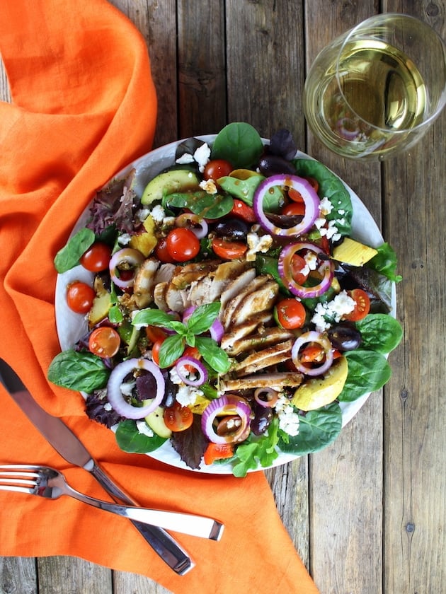 Grilled Mediterranean Chicken Salad with orange napkin and silverware