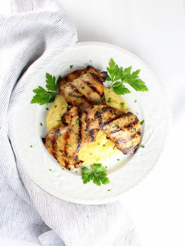 Wide view dinner plate with Grilled Rosemary Lemon Chicken Thighs on parmesan polenta