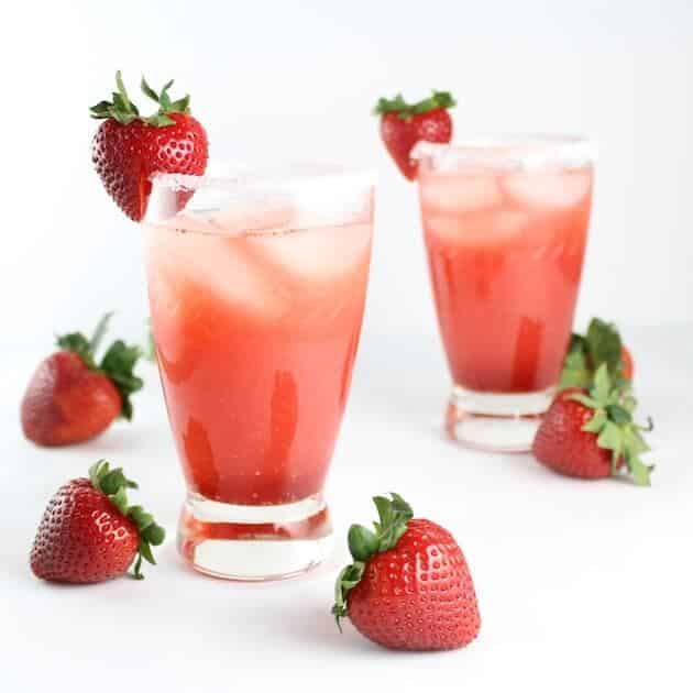 Two Fresh Strawberry Margaritas surrounded by strawberries