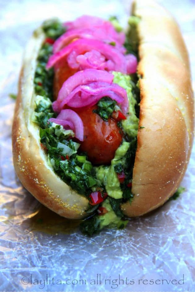 Eye level Chorizo hot dog with pickled red onions and chimichurri green sauce