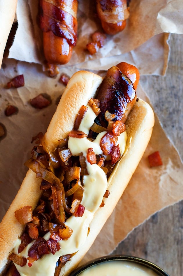 Hot dog wrapped in Bacon with melted cheese on a piece of brown parchment