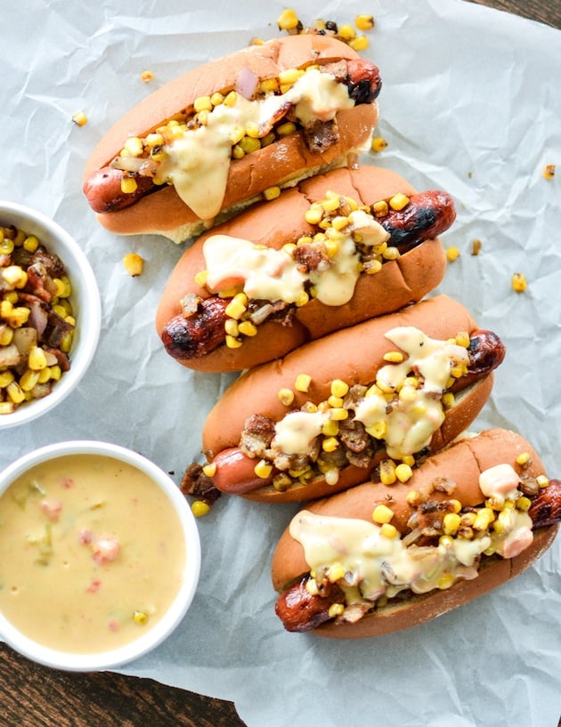 4 Hotdogs on parchment paper with ramekin of queso