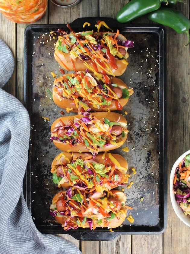 Five hot dogs asian slaw, ketchup and mustard on a cookie sheet