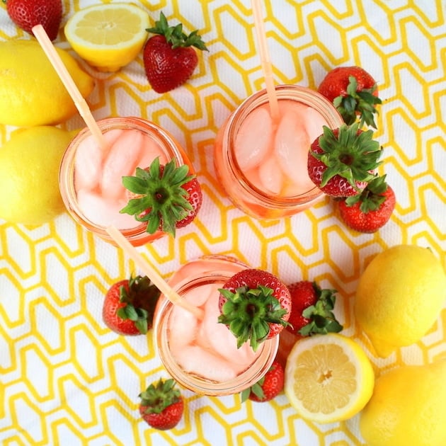 Mason jars with Strawberry Lemonade on yellow patterned tablecloth
