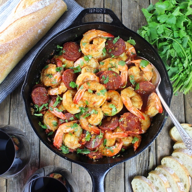 Sun-Dried Tomato Chorizo Garlic Shrimp in cast iron skillet with baguette and red wine