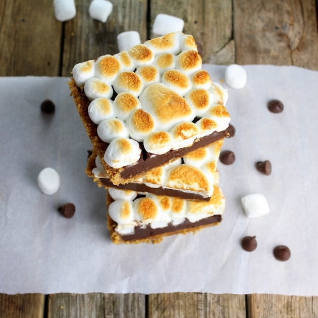 Overhead view of three stacked Baked Nutella S\'mores squares surrounded by mini marshmallows and chocolate chips