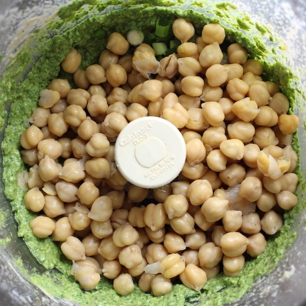 Adding chick peas to food processor for green hummus, before mixing