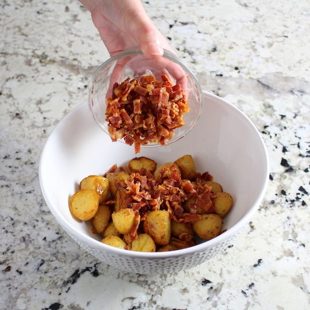 Adding bacon to potatoes in mixing bowl