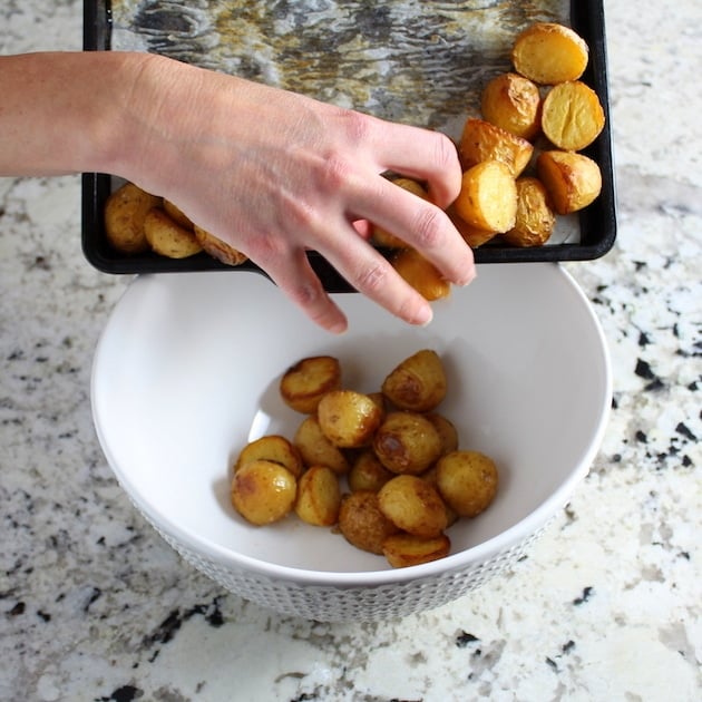 Adding baked baby potatoes to mixing bowl