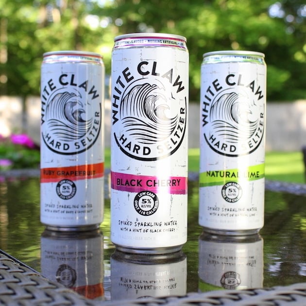 Three cans of White Claw Hard Seltzer eye level in backyard