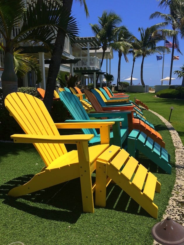 Bright colorful Adirondack chairs on green lawn with palm trees at Southernmost Beach Resort in Key West