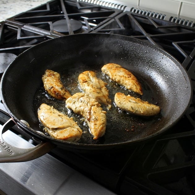 Chicken tenders sauteeing in pan on stovetop