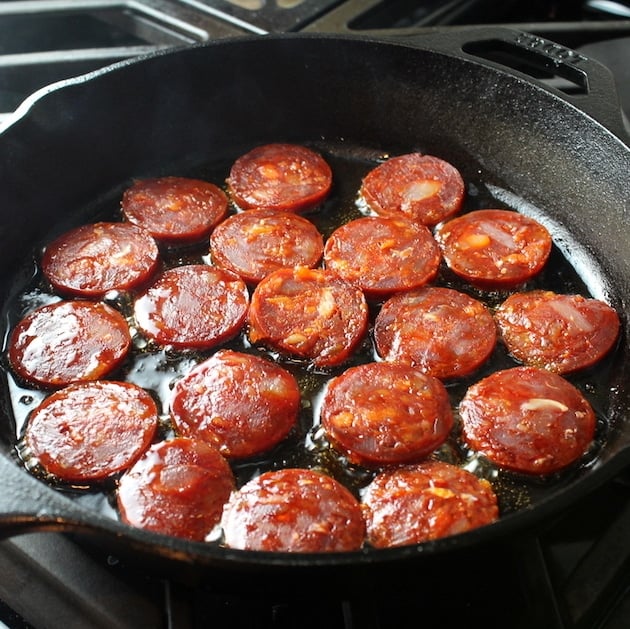 Chorizo sauteeing in cast iron skillet on stovetop