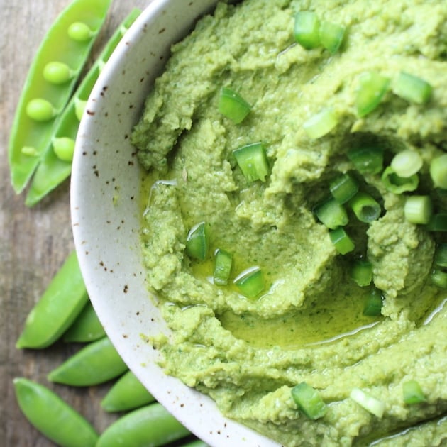 Partial bowl of Spicy Green Hummus with chopped onions and olive oil