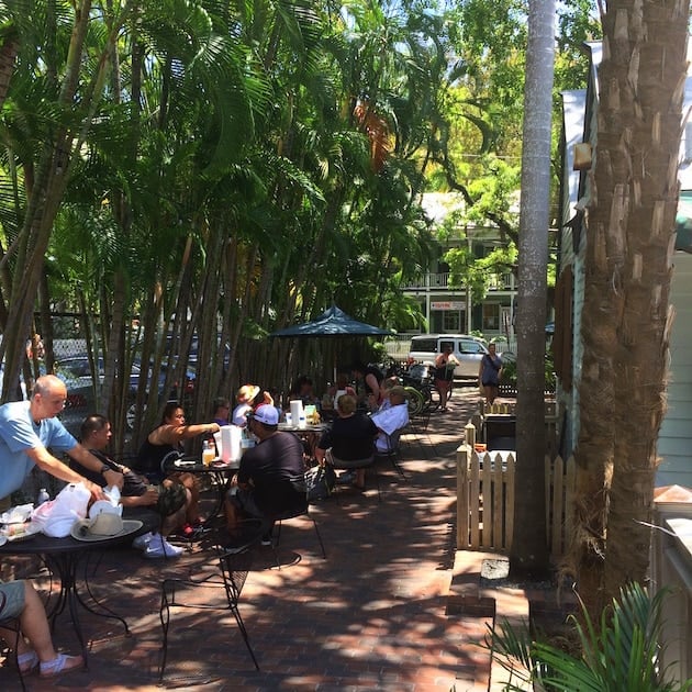 People eating at outdoor tables in tropical setting at Key West Garbo\'s Grill