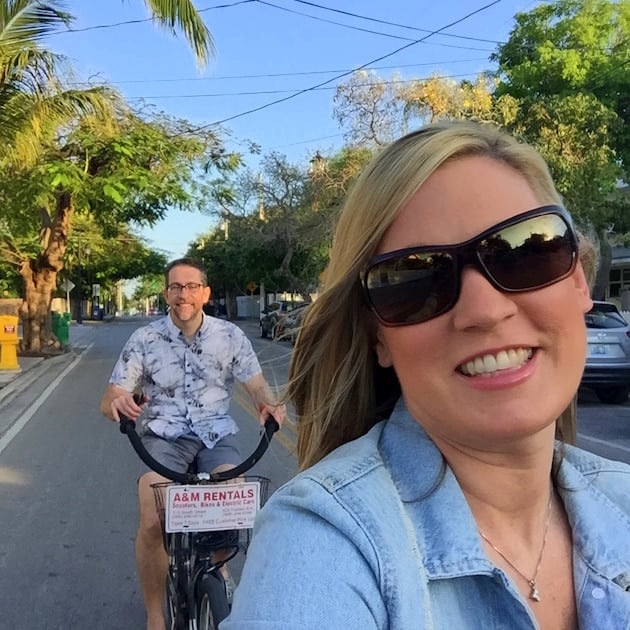 Man and woman riding bikes on a street in Key West