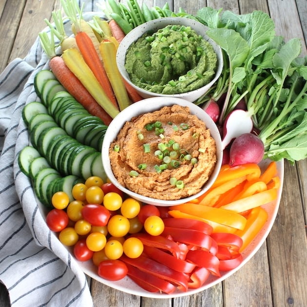 Platter loaded with fresh veggies, Sun-Dried Tomato Goat Cheese Dip and Spicy Green Hummus