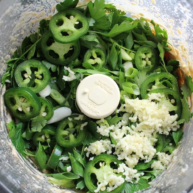 Adding jalapenos, parsley, and garlic to food processor before mixing