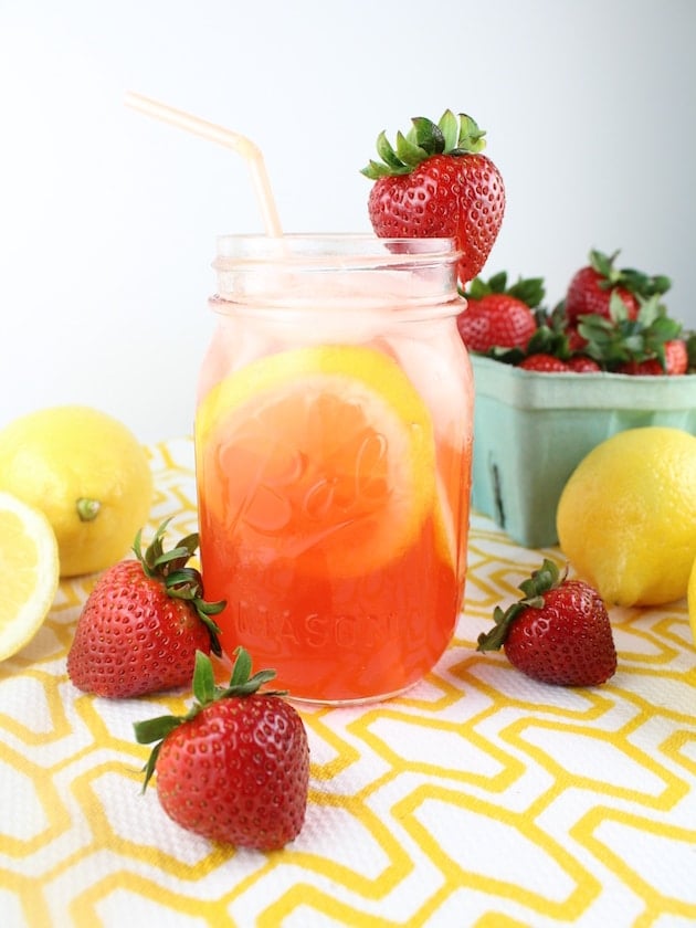 Mason jar of Strawberry Lemonade with fresh strawberries in the background