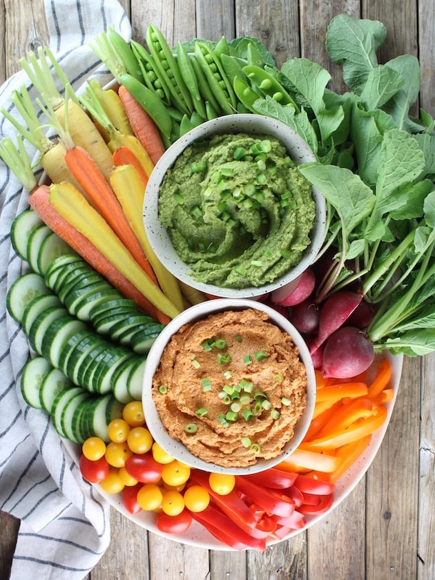 Platter full of veggies with two bowls of dip