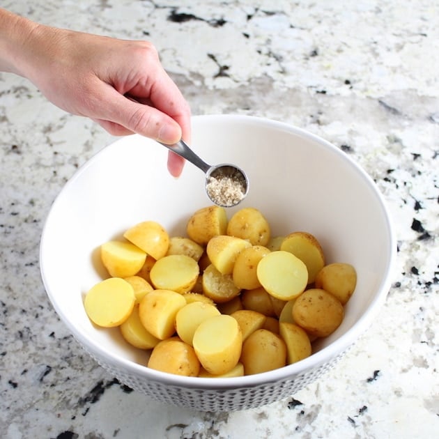 Adding seasonings to bowl of potatoes