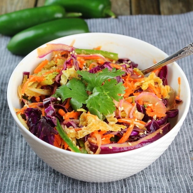 Bowl of asian slaw with jalapenos in the background