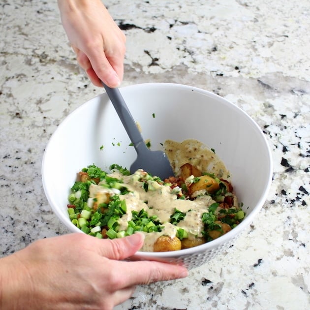 Stirring together potato salad in mixing bowl