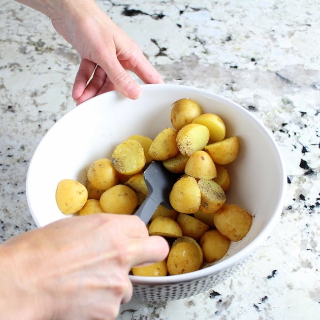 Stirring seasonings into bowl of cut up potatoes