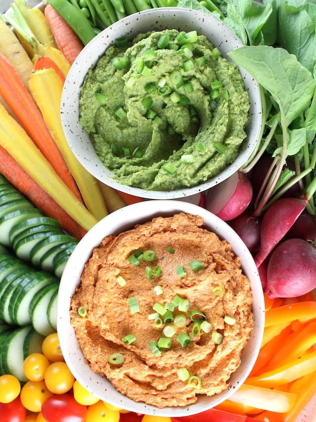Sun-Dried Tomato Dip and Spicy Green Hummus bowls on platter full of colorful fresh vegetables