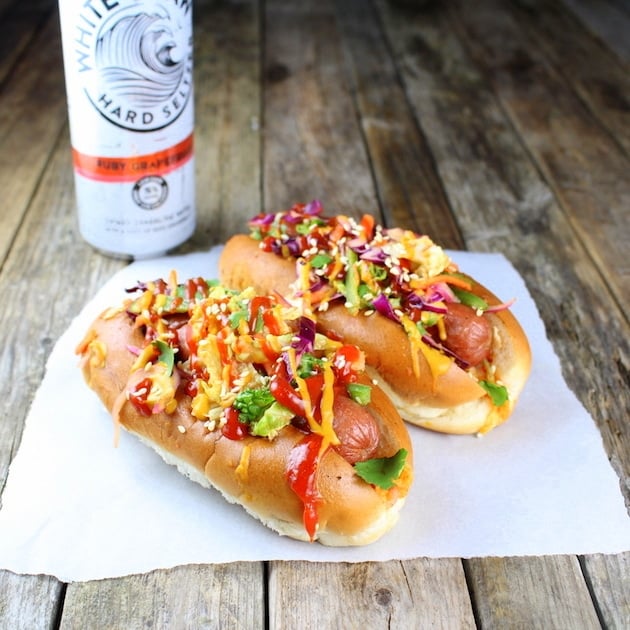 Two Asian Slaw Dogs on parchment with can of seltzer in background