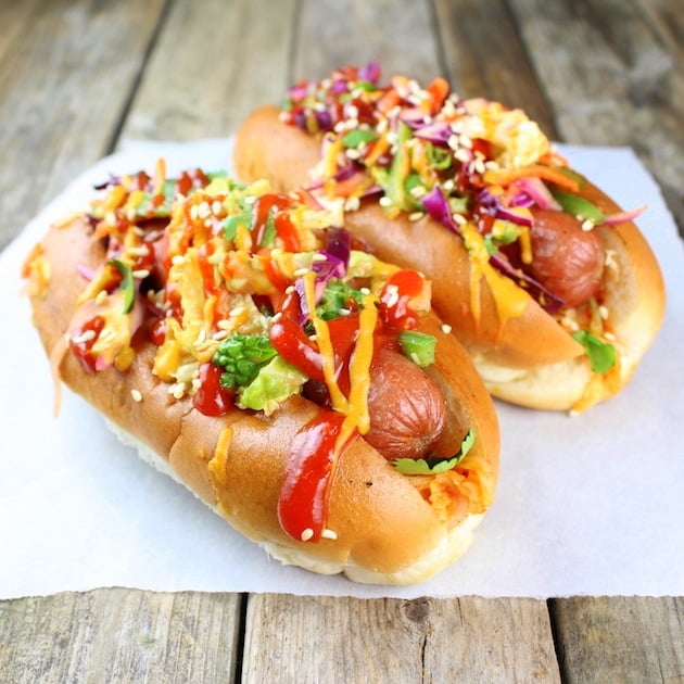 Two Korean Slaw Dogs with sesame seeds on parchment 