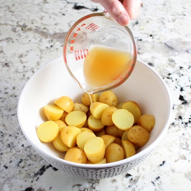 Adding stock to cut up potatoes in mixing bowl