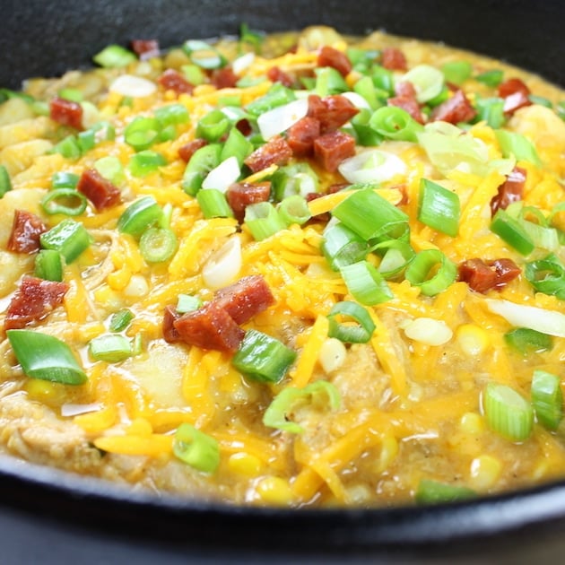 Soup pot of Corn Chowder with shredded cheddar, chopped green onions, and chorizo on top