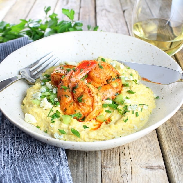 Bowl of Buffalo Shrimp and Blue Cheese Grits with glass of white wine