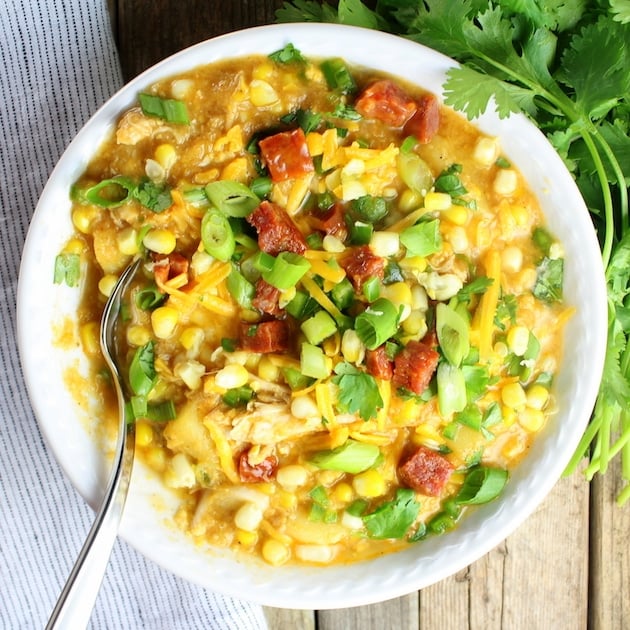 Spoon in a bowl of Corn Chowder with chicken, onions, and cheddar