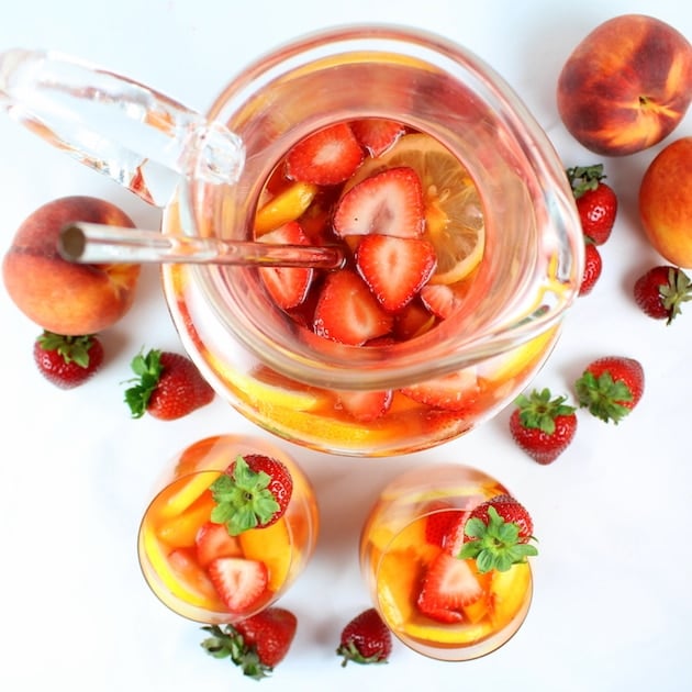 over top glass pitcher of sangrial with peaches and strawberries
