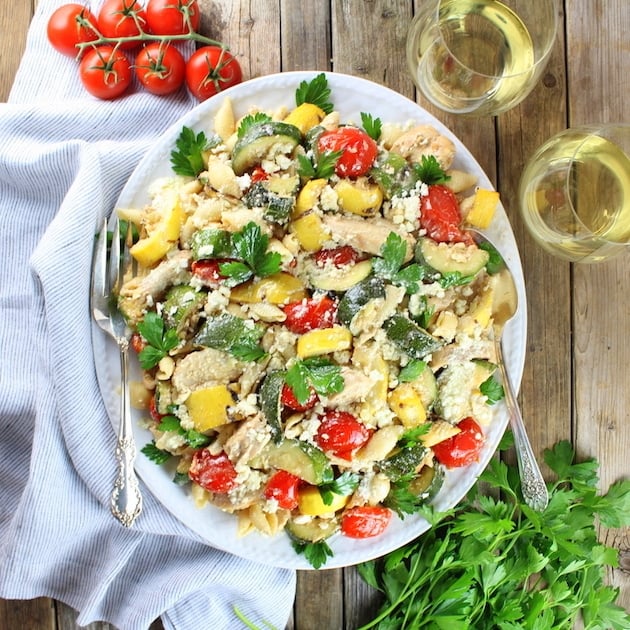 Serving dish of Grilled Chicken and Squash with Tomato Feta Pasta on farm table