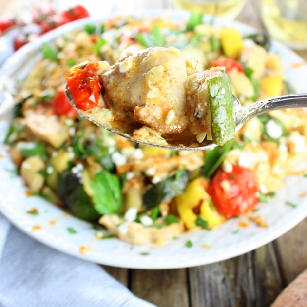 Spoonful of Grilled Chicken and Squash with platter of Pasta and vegetables in background