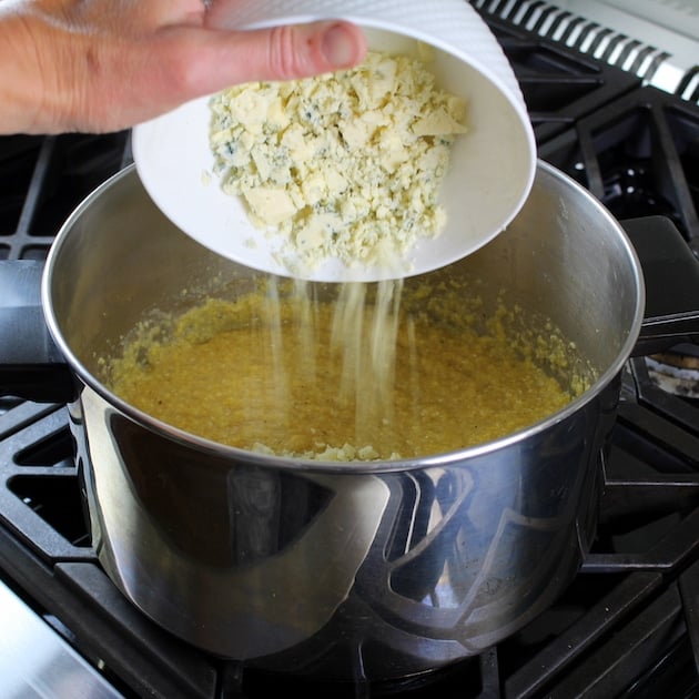 Adding blue cheese to polenta on stovetop