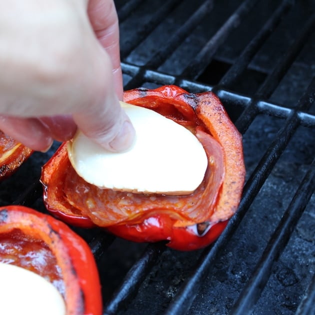 adding fresh mozzarella to red bell peppers on the grill