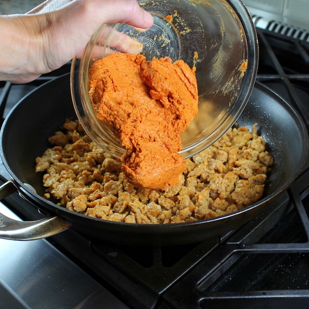 Adding sundried tomato sauce to ground meat in a skillet