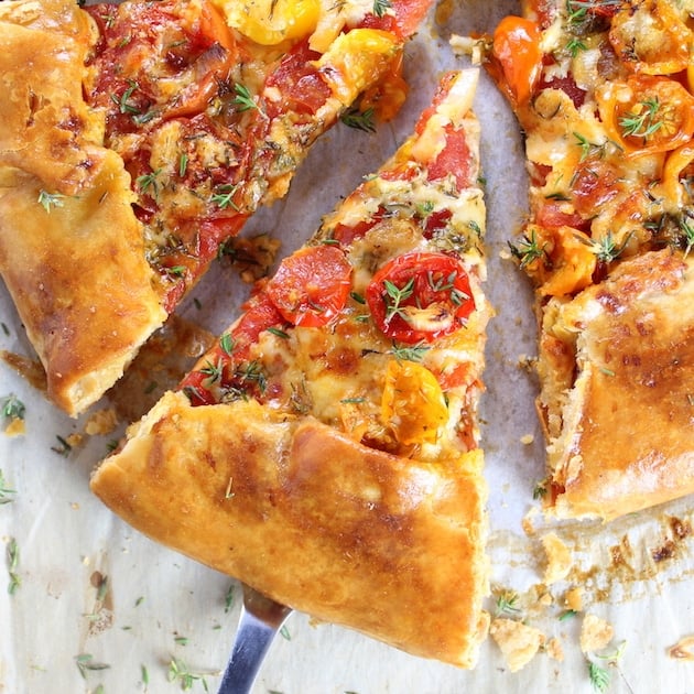 Three Cheese Tomato Thyme Galette piece of pizza on a spatula