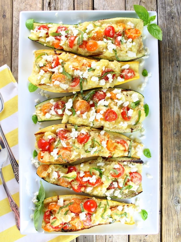 grilled squash stuffed with tomatoes and feta, lined up on a serving platter